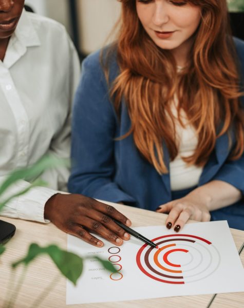 Multiracial colleagues working on their project and looking at documents in an office. Business professionals meeting in office. Focus on a diverse woman hands pointing on charts on a desk.